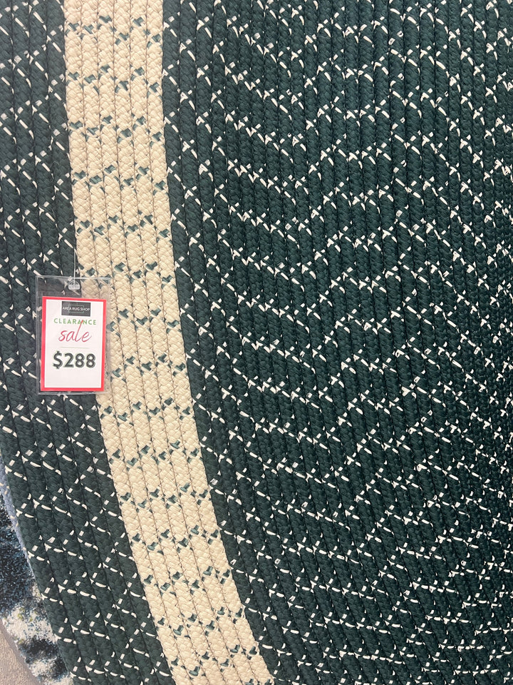 Close up Oval braided rug in forest green with beige border, made of durable polypropylene
