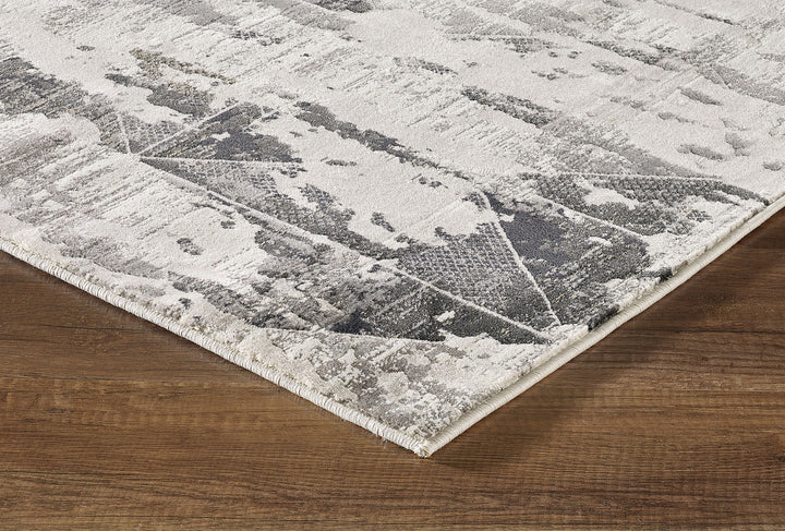 A contemporary area rug with a geometric pattern in gray, black, and ivory tones.